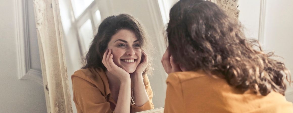 Positives Selbstbild: Frau lächelt in den Spiegel